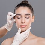 Cosmetologist Examining Facial Wrinkles on Young Woman Face